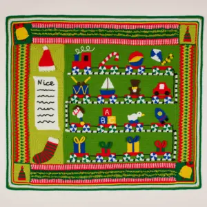 A festive crocheted Christmas blanket featuring a green "Santa's Workshop" scene with toys, candy canes, and a "Nice" list.